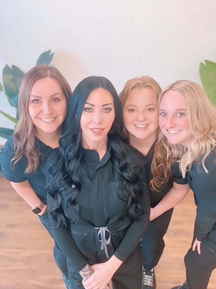 Group of four staff members smiling together in the clinic.